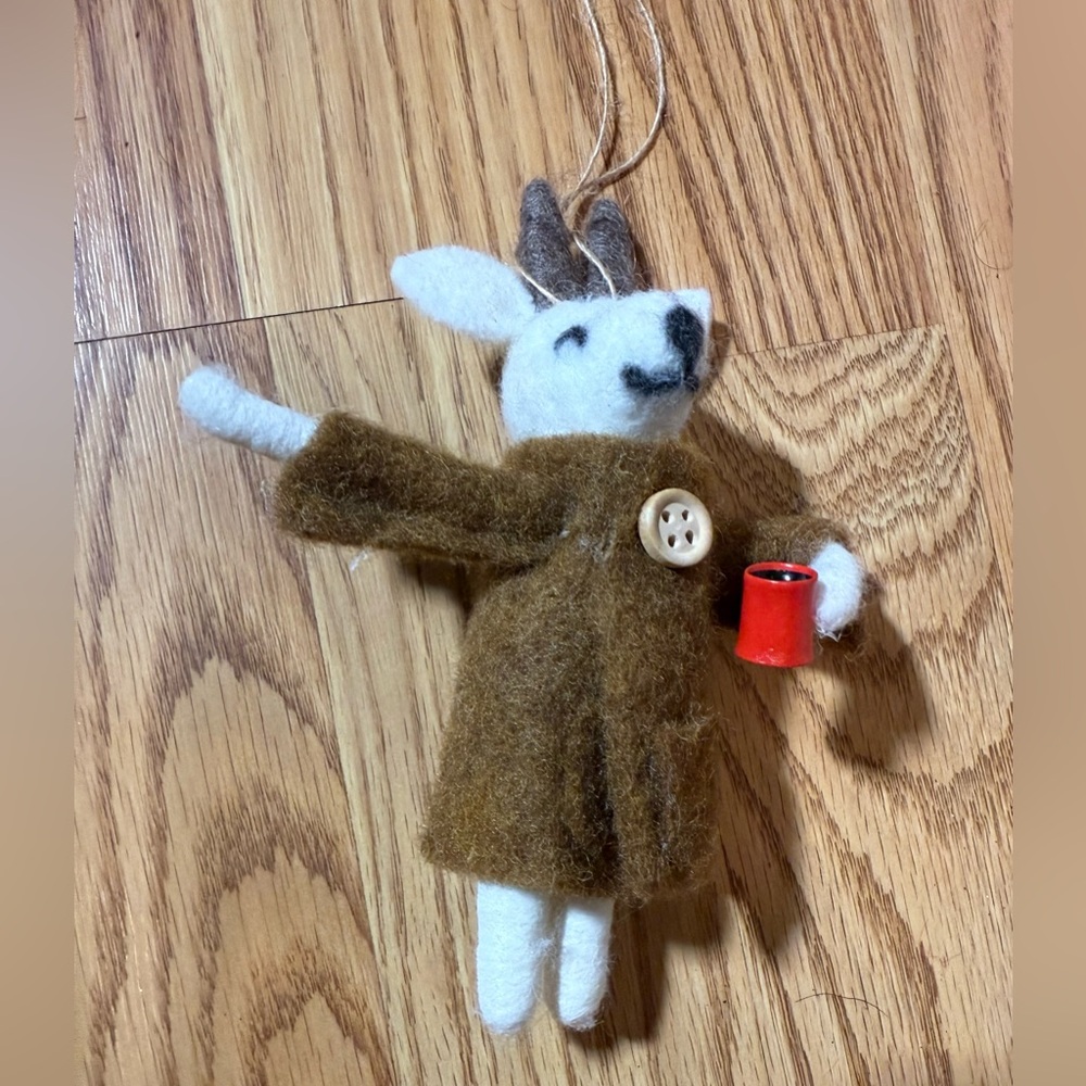 A handcrafted, needle-felted wool mouse ornament holding a red cup.